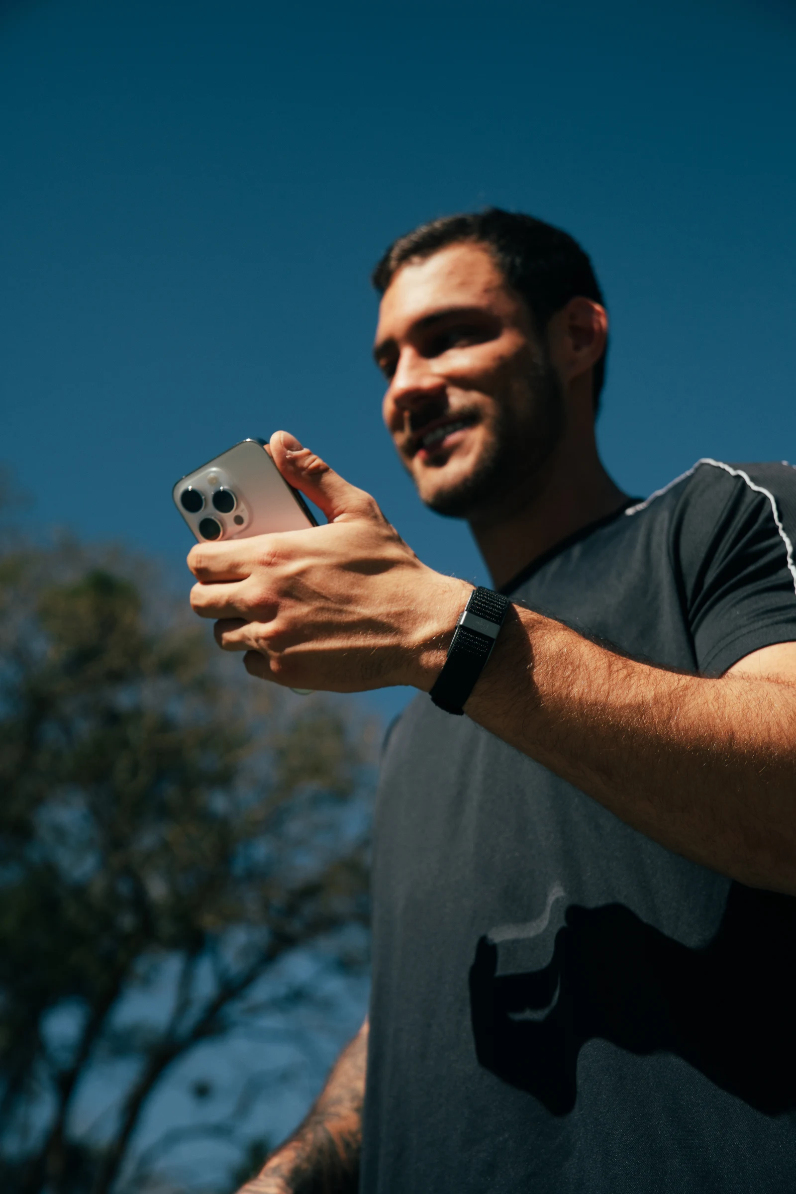 Homem com a pulseira consultando o celular ao ar livre